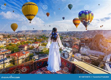 Beautiful Girl Standing On The Hotel And Looking To Hot Air Balloons In