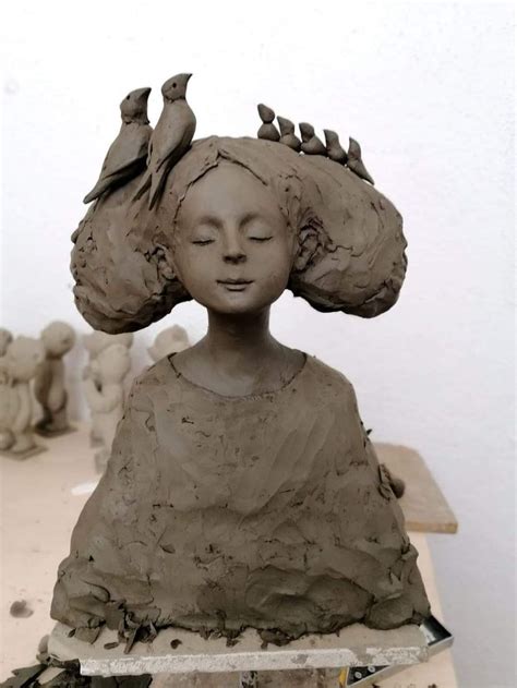 A Clay Sculpture Of A Womans Head With Birds Perched On Her Hair