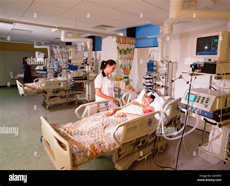 Hospital Nurses Tending To Male Patients In Intensive Care Unit Stock