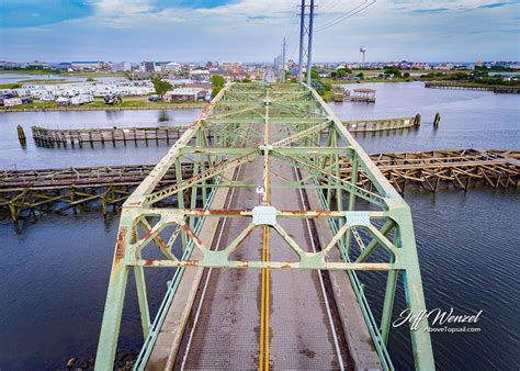 A structure spanning and providing passage over a gap or barrier, such as a river or roadway. JW084: Swing Bridge Island Time Begins - Above Topsail