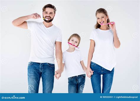 Familia Feliz En Las Camisetas Blancas Que Limpian Los Dientes Con Los Cepillos De Dientes