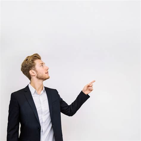 Portrait Of Young Businessman Pointing At Something Looking Up Photo
