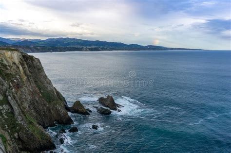 Jagged And Rocky Ocean Coast With Cliffs And A Rainbow Stock Photo