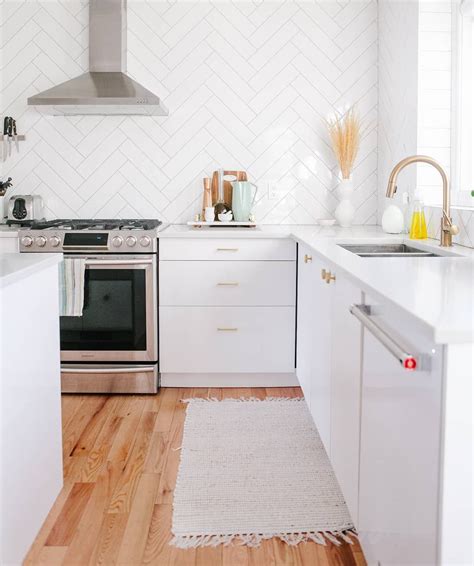 Rectangles are arranged in a herringbone pattern on. Simple white kitchen with wood floor and herringbone tile ...