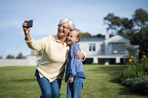 Grandmother And Granddaughter Taking Selfie With Mobile Phone In Garden