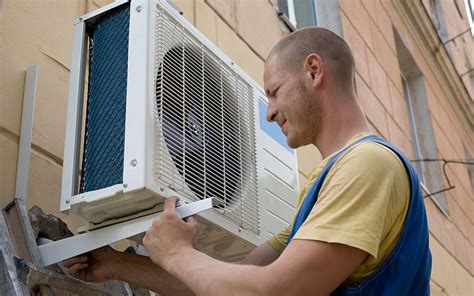 A Man Installing The Outdoor Unit Of A Mini Split Air Conditioner On