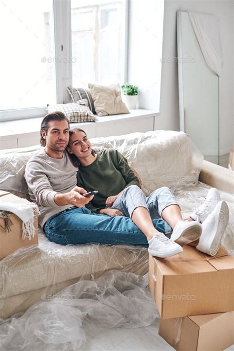 Happy Young Restful Couple Relaxing On Couch While Sitting In Front Of Tv Set Couples Sitting
