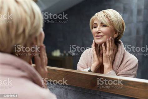 Skincare Routine Mature Woman Touches Face Skin In Front Of The Mirror
