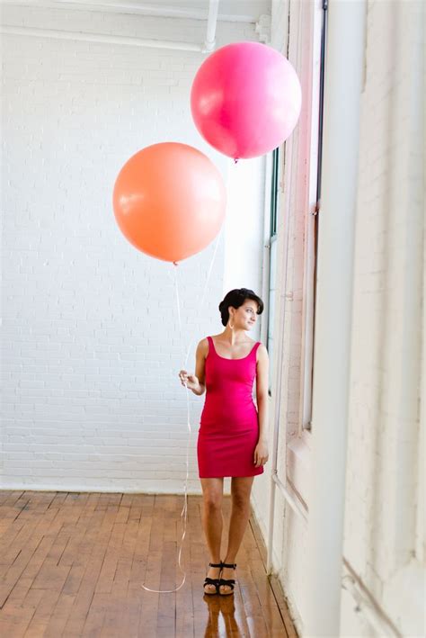 A Woman In A Pink Dress Holding Two Balloons