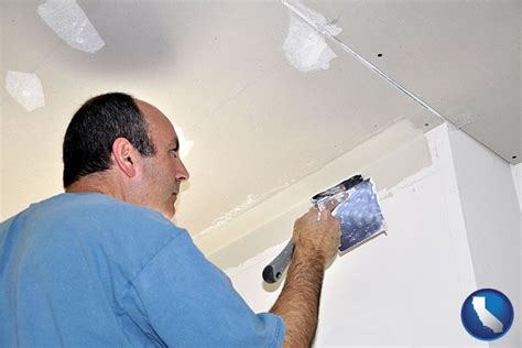 A Man Is Painting The Ceiling With White Paint On It And He Is Holding