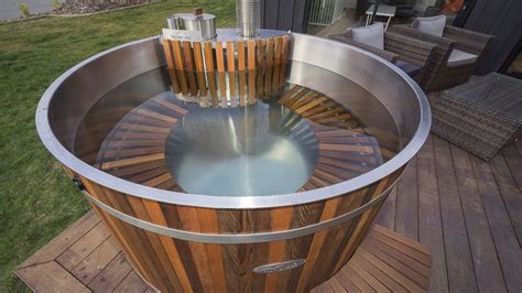 A Wooden Hot Tub Sitting On Top Of A Wooden Deck Next To A Lawn Area