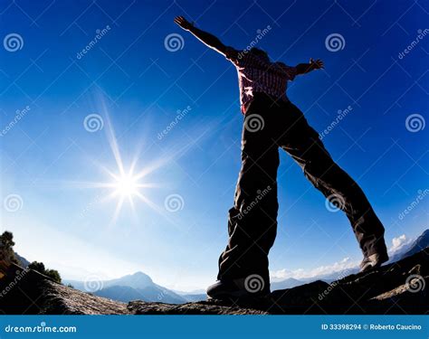 Man Opens His Arms In The Sunshine Against Blue Sky Stock Photo