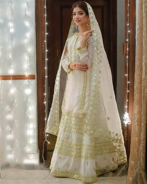 A Woman Wearing A White And Yellow Bridal Outfit With Lights In The