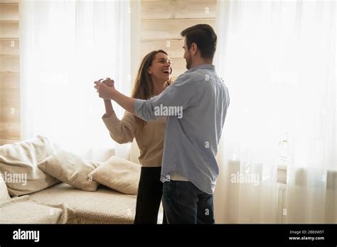 Romantic Young Married Couple Dancing To Favorite Slow Music In Living