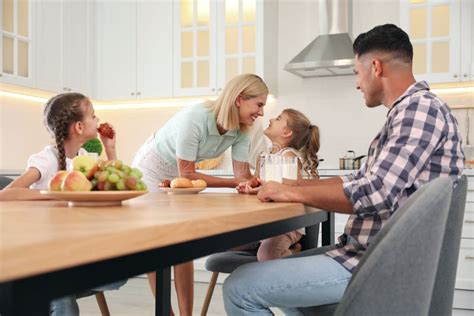 Familia Feliz Comiendo Juntos En La Mesa En Cocina Moderna Imagen De