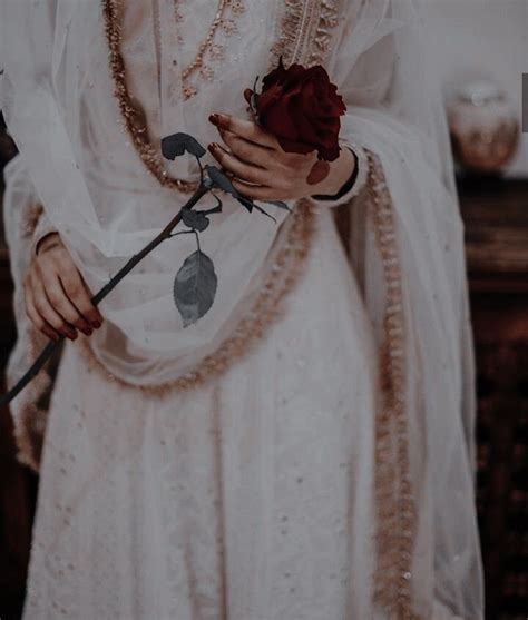 A Woman Dressed In White Holding A Rose