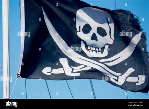 The Jolly Roger Skull And Swords Pirate Flag On Blue Sky Background