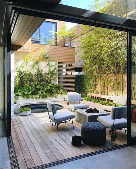 A Modern Patio With Lots Of Greenery A Hot Tub A Concrete Firepit