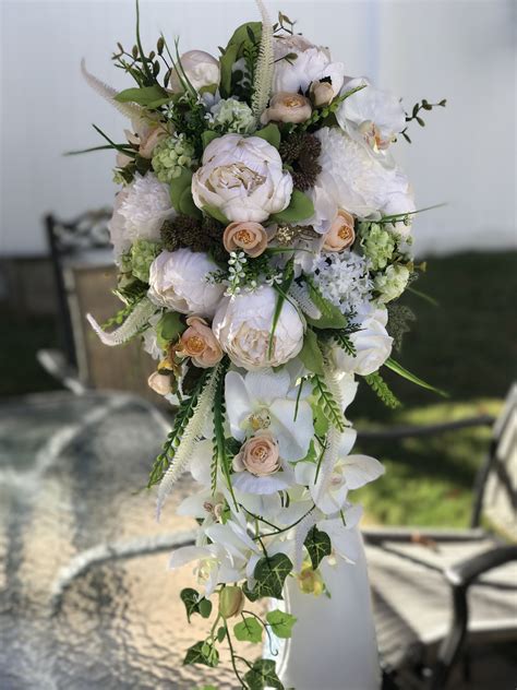 A Bouquet Of White Flowers On Top Of A Glass Table Outside With Chairs