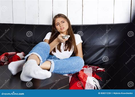Bored Pretty Girl Watching Tv Sitting On Sofa At Home Stock Photo