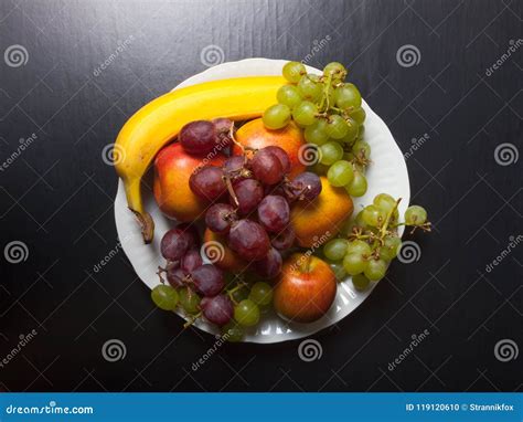 Different Types Of Fruits On A White Ceramic Plate On A Black Ba Stock