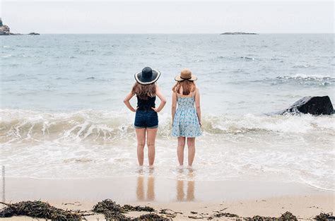 Two Girls Getting Their Feet Wet In The Ocean By Stocksy Contributor