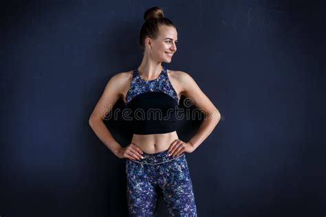 Beautiful Fitness Model Is Posing In Front Of The Dark Wall In A Dark Training Suit Stock Image