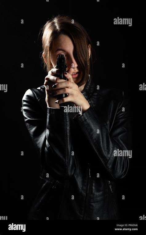 Serious Girl With Gun On Black Background Aiming At Camera Stock Photo
