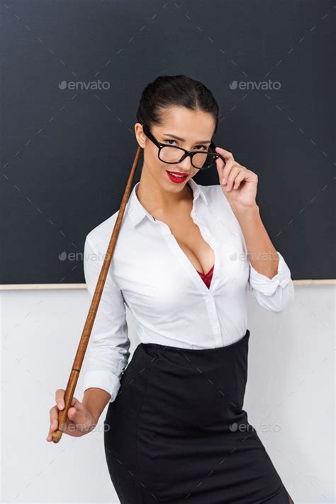 Young Sexy Teacher With Wooden Pointer Standing In Front Of Chalkboard