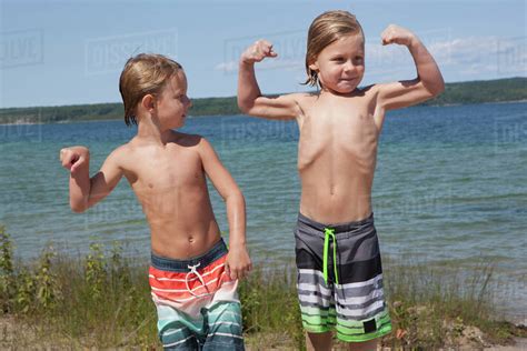 Caucasian Boys Flexing Muscles On Beach Stock Photo Dissolve