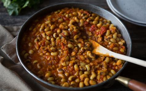 A Pot Filled With Beans And Sauce On Top Of A Wooden Table