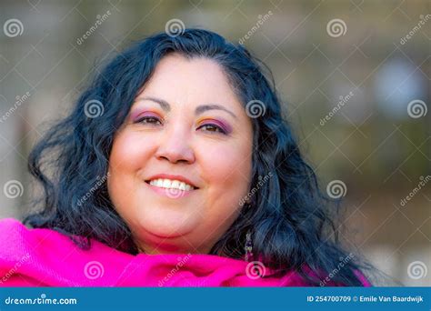 Portrait Of The Face Of A Beautiful Chubby Mexican Woman Smiling Against A Blurred Background