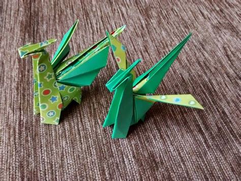 two green origami birds sitting on top of a brown carpeted floor next