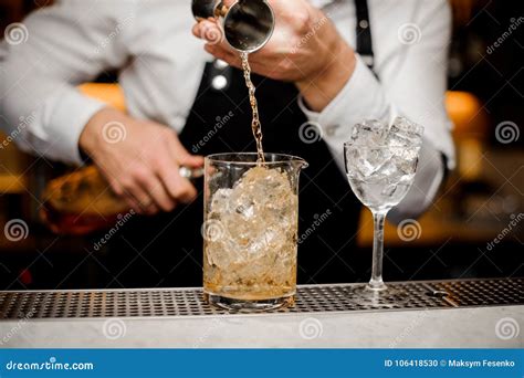 Bartender Pouring Alcoholic Drink Into A Large Glass Filled With Ice