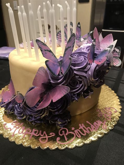 A Birthday Cake Decorated With Purple Flowers And Butterflies On A Gold