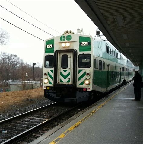 A Green And White Train Pulling Into A Station Next To A Person