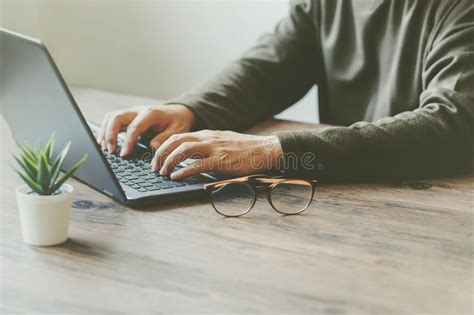 Man Typing On A Laptop Keyboard On A Wooden Table And Tree Stock Image