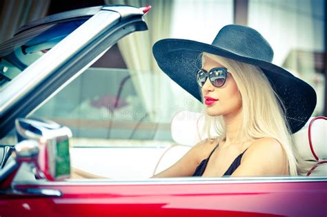 openlucht de zomerportret van modieus blonde uitstekende vrouw die een convertibele rode retro
