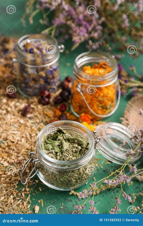 Jars With Aromatic Dried Herbs And Flowers On Color Table Stock Photo