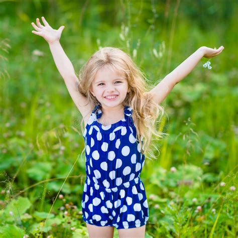 Little Girl With Long Blond Curly Hair And Raised Hands Stock Photo