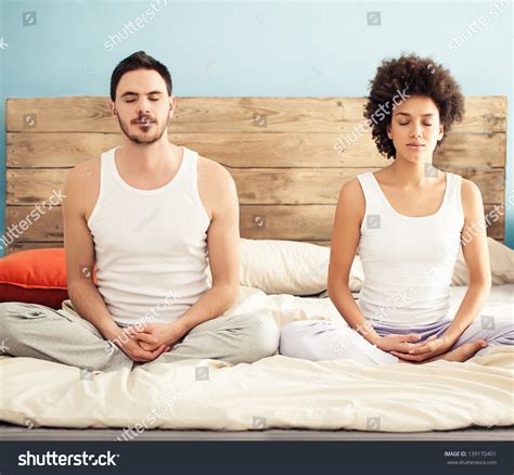Young Mixed Race Couple Meditating Together In Their Bedroom Stock