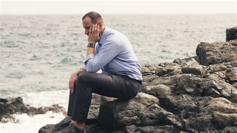 Sad Man Sitting Alone On Rocks Next To The Sea Stock Footage Video
