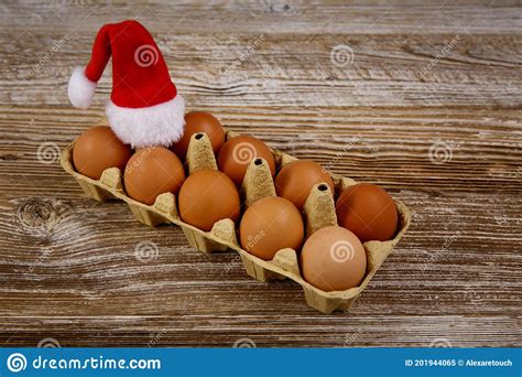 una docena de huevos en una tabla de madera y un huevo con sombrero de santa imagen de archivo