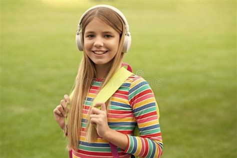 Happy Teenage Girl In Headphones Back To School Carrying Backpack