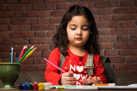 Premium Photo Indian Small Girl Drawing Or Painting With Colours Over