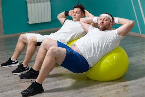 Tired Fat Man Is Lying On A Fitness Ball Training During Group Fitness