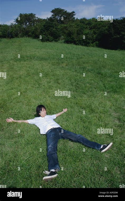 Ein Junger Mann Liegt Auf Dem Rasen Mit Seiner Arme Und Beine Weit