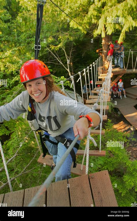 Young Woman Crossing Rope Bridge In Rainforest Canopy Near Ketchikan