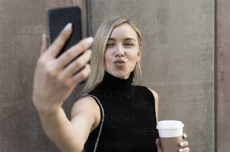 Portrait Of Blond Woman With Coffee To Go Taking Selfie With Smartphone