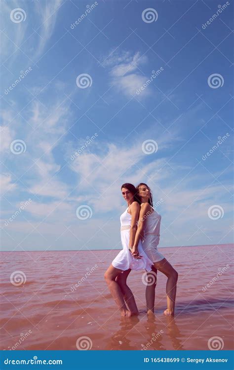 Two Hot Brunettes In A White Dresses Posing Near The Lake Stock Image